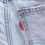 Detailaufnahme einer klassischen Levi’s-Jeans mit dem charakteristischen roten Levi’s-Etikett an der Gesässtasche. Diese Positionsmarke steht für Authentizität, Tradition und Markenwiedererkennung. Das leuchtend rote Etikett, kombiniert mit der hellblauen Denim-Struktur und den auffälligen, orangefarbenen Kontrastnähten, ist ein unverkennbares Markenzeichen, das Levi’s weltweit als Original identifiziert.