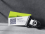 abonax Visitenkarte in grün mit QR-Code und Kontaktinformationen, präsentiert neben einer Kamerarolle auf grauem Hintergrund.