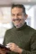 Patrick Castellani von we dot lächelt mit einem Tablet in der Hand in den hellen Räumen der Agentur